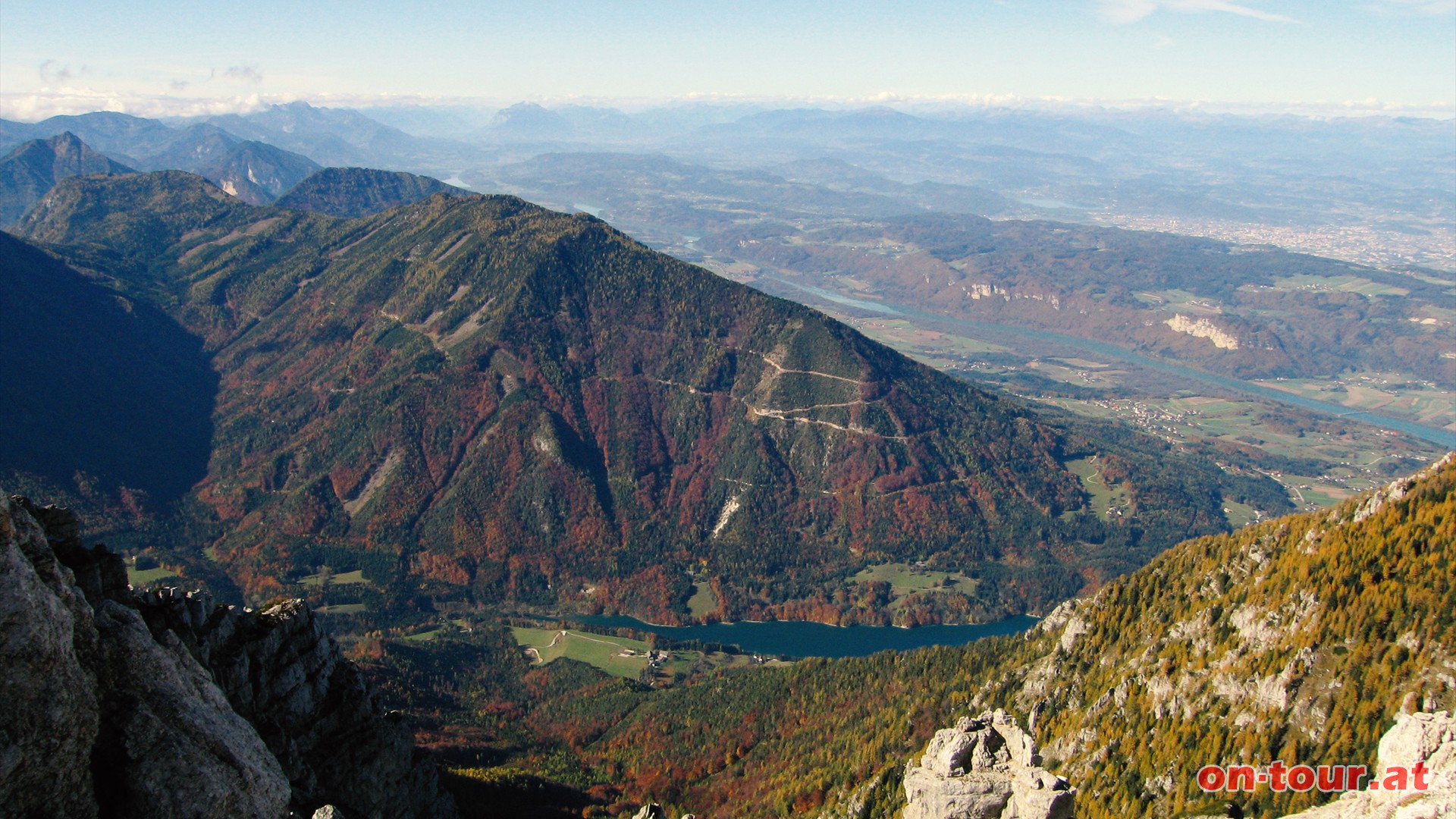 Der Freibach-Stausee im Tal und rechts ber der Drau liegt Klagenfurt.