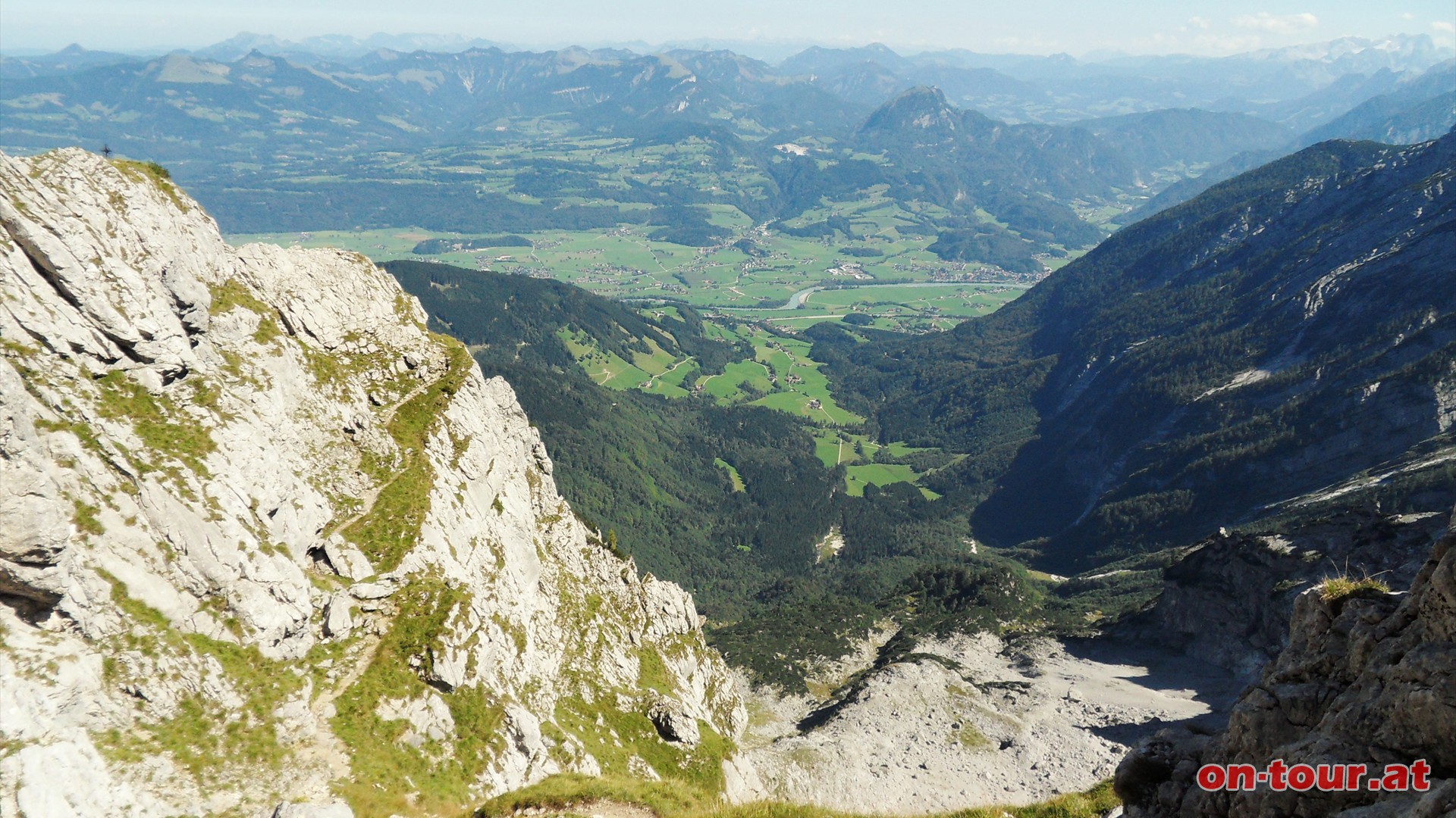 Herrlicher Tiefblick hinunter nach Golling und zur Salzach. Links die abfallende Wand zum Wilden Freithof, das Kreuz am Grat und der Wanderweg am Felsband.