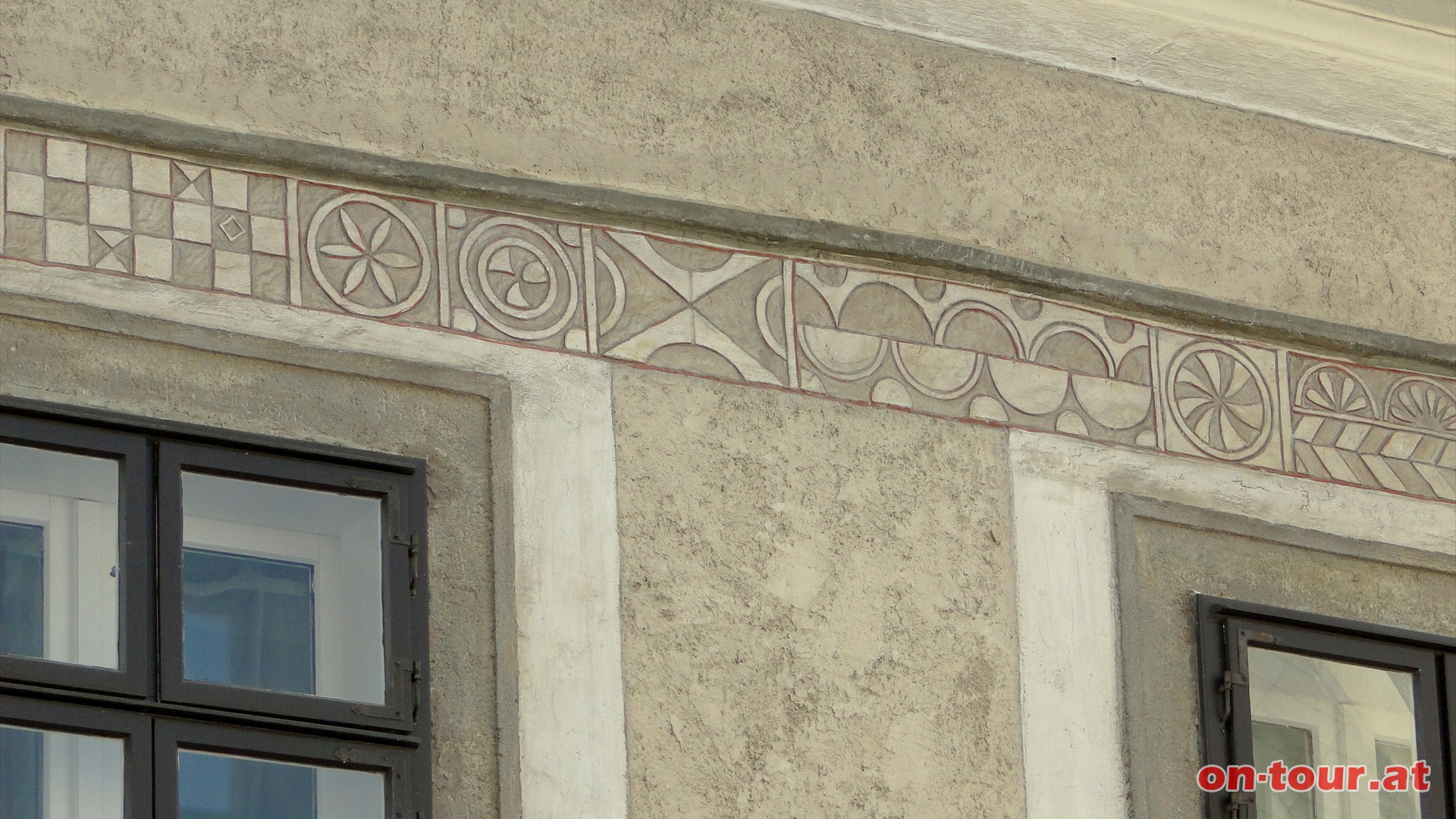 Ein unterschiedlich gestaltetes Fries ziert die Hausfassade.