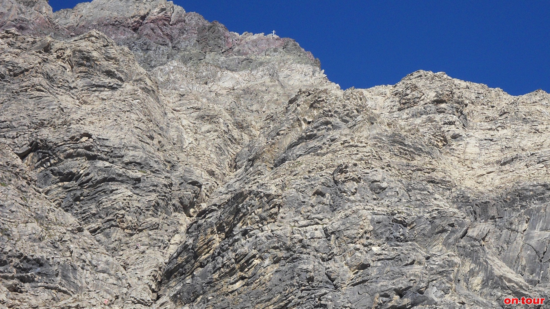 Die Wand am Ende der Gasillschlucht. Oben das Gipfelkreuz der Parseierspitze.