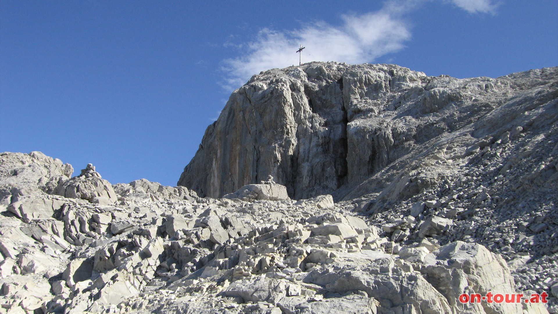 Vor der steilen Nordflanke fhrt der Weg rechts am Gipfelaufbau vorbei, um schlielich am Westrcken links zum Ziel zu fhren.